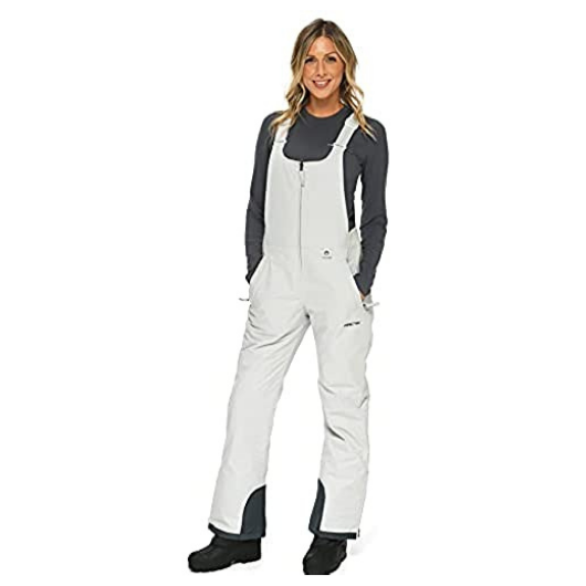 Front view with hands in the pocket of woman wearing Arctix snow bibs in Quiet Gray