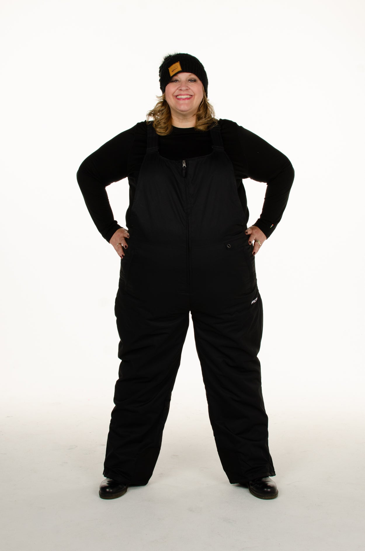 Plus Size Woman wearing black Arctix snow bibs with hands on hips