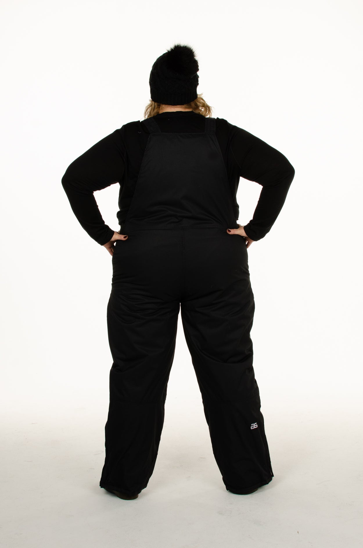 Plus size woman back view of  Arctix black snow bibs in black