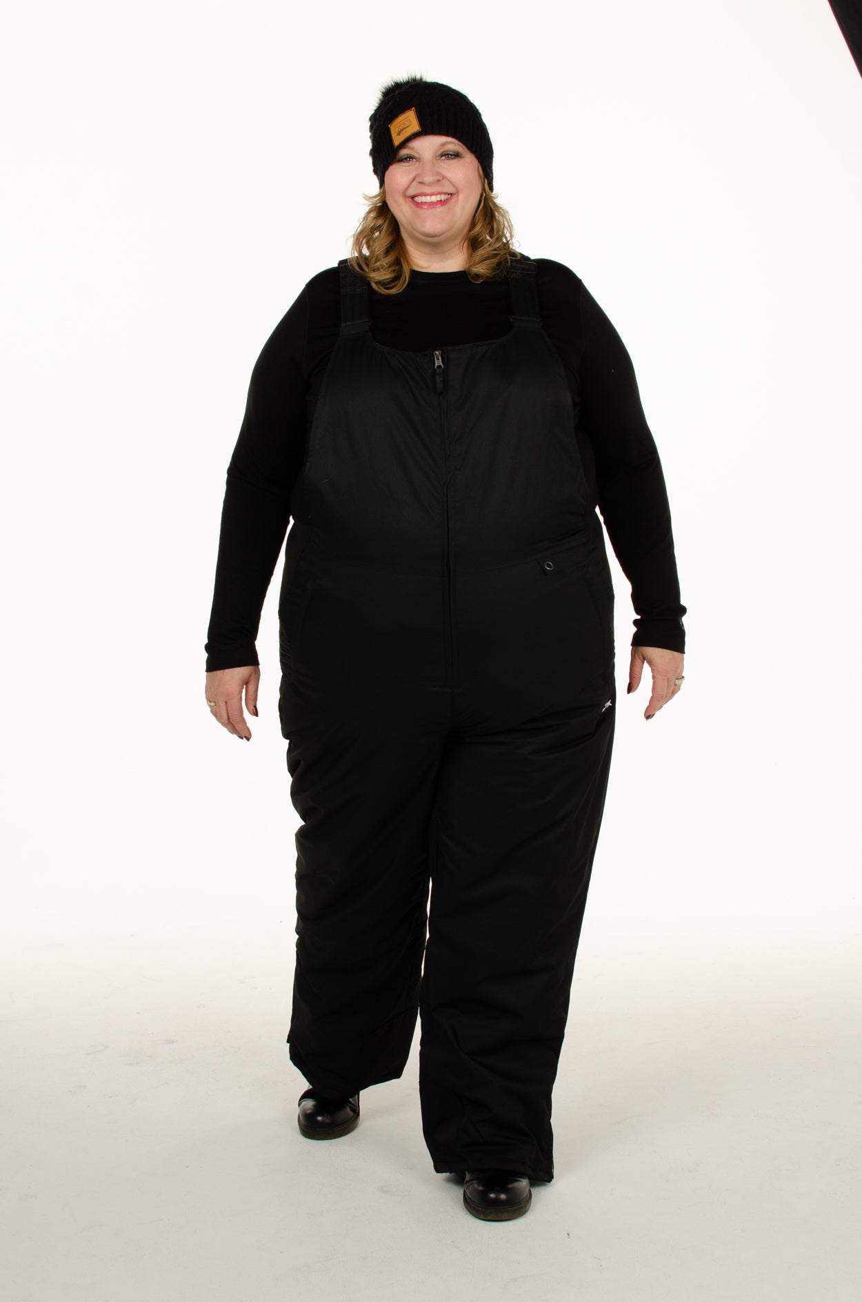 front view of plus size woman wearing  Arctix black snow bibs walking