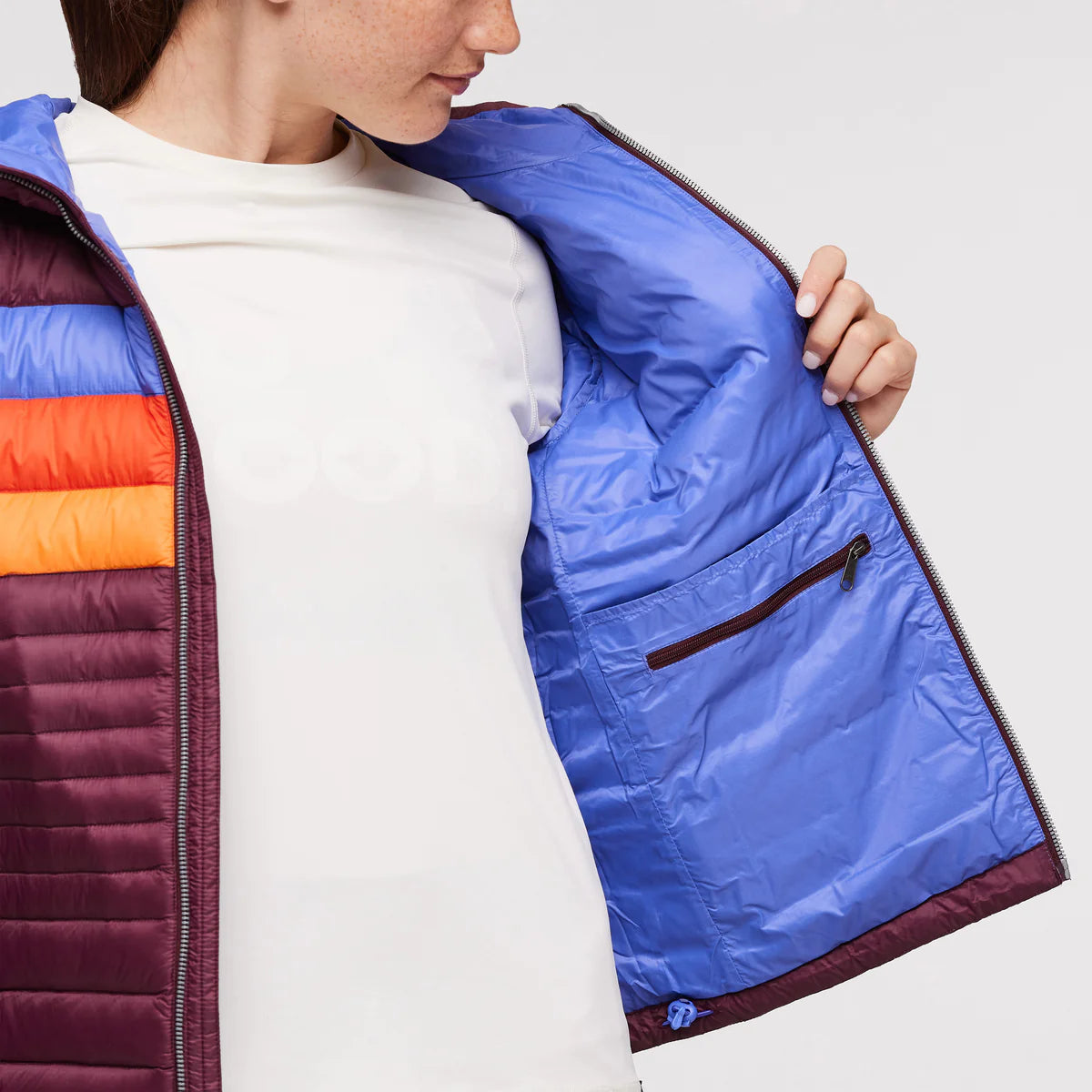 Inside pocket view of woman wearing Cotopaxi Fuego Down Plus Size Hooded Jacket in Wine Stripes