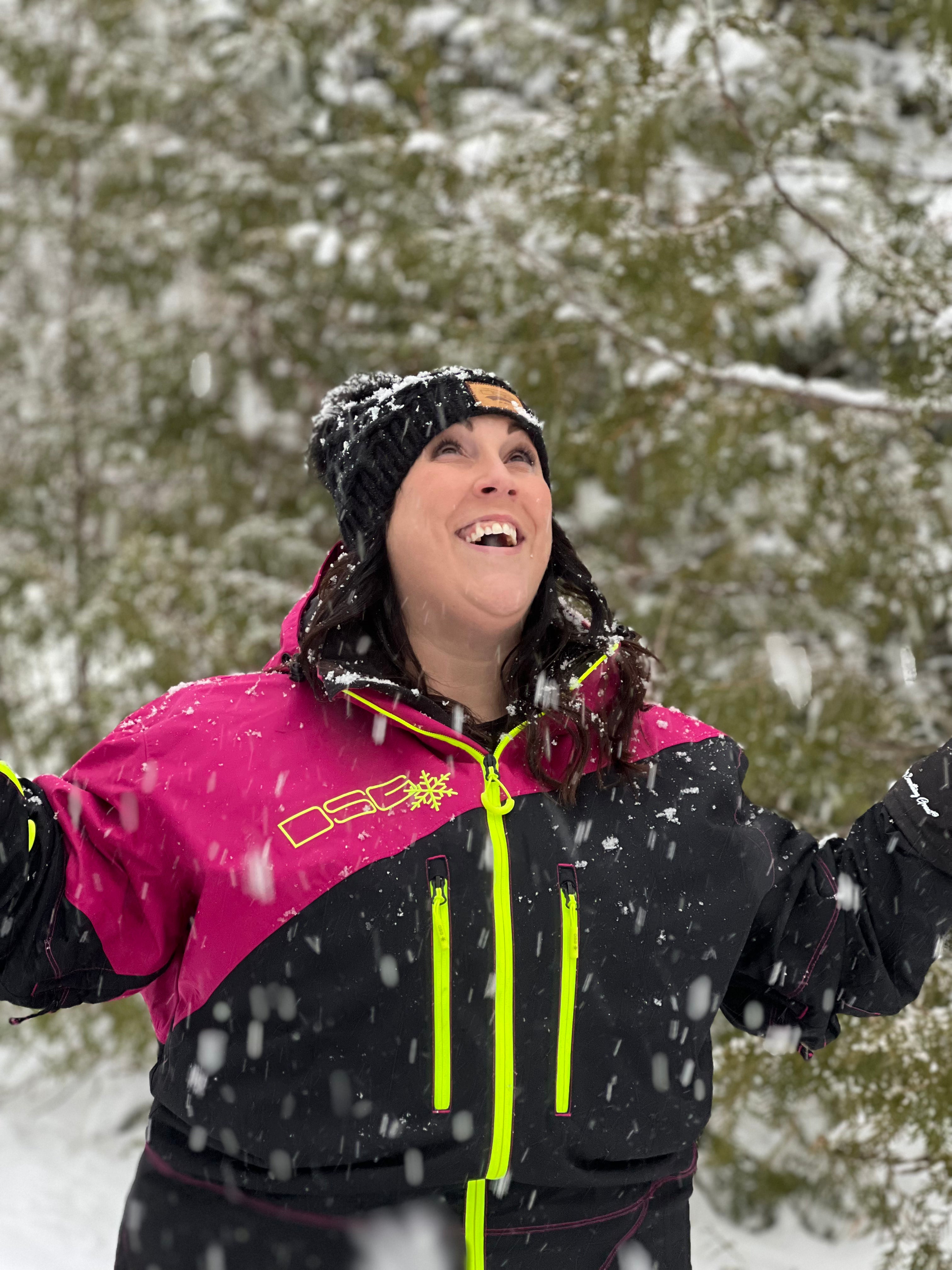 Plus size woman looking up at the sky while it's snowing and smiling