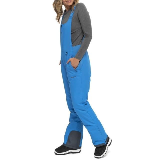 Left side view of Woman wearing Arctix snow bibs in Marine Blue 